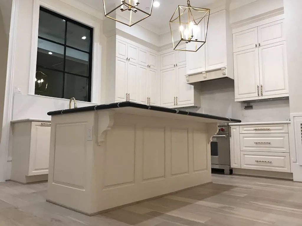 RM white kitchen cabinetry with a paneled island and dark countertop, photographed on site.
