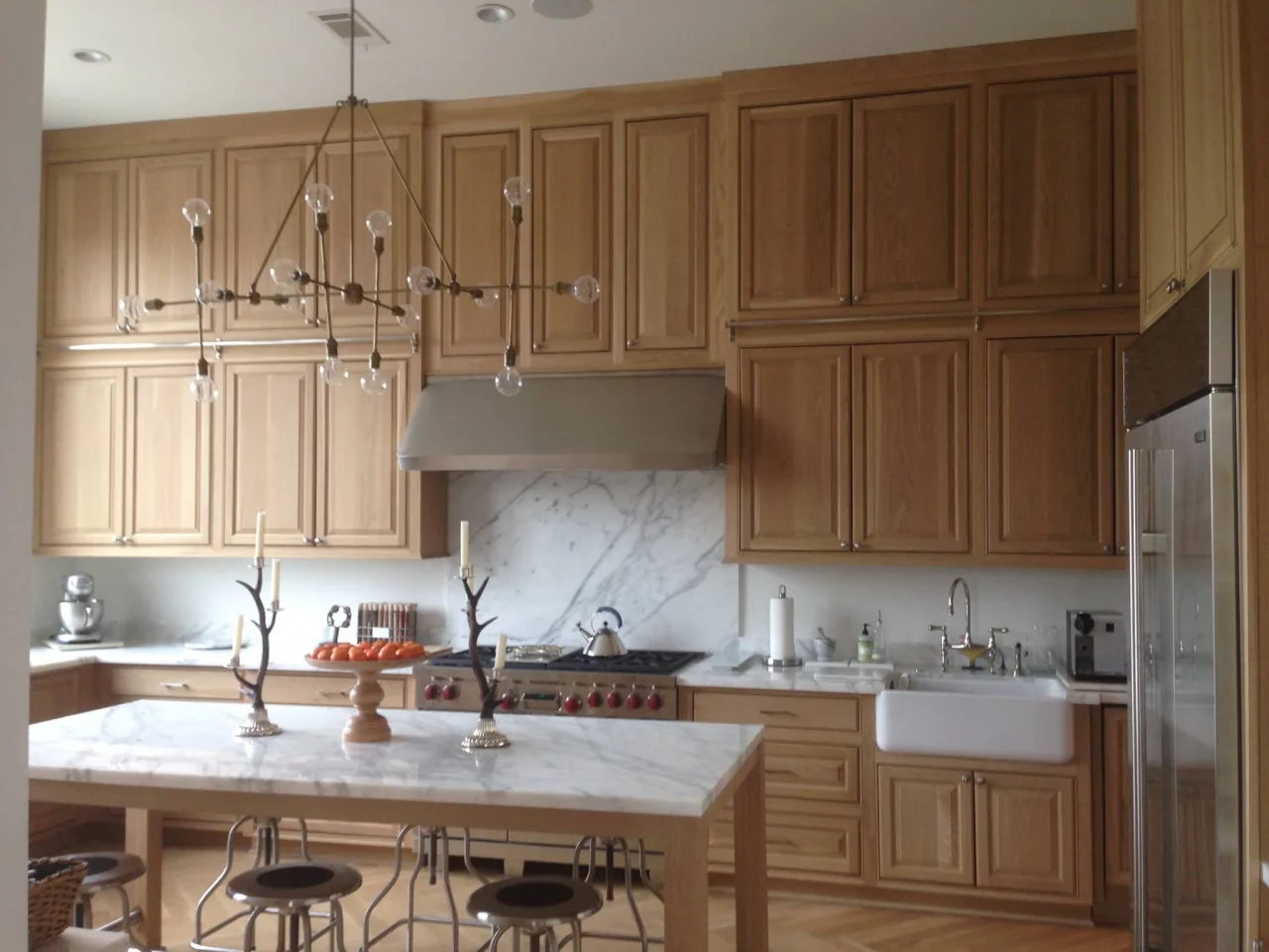 RM kitchen with tall wood cabinets, a light-topped island and a farmhouse sink.