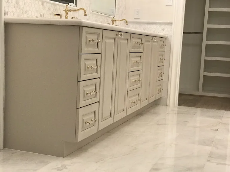 RM bathroom vanity with cream cabinet doors, rows of drawers and decorative brass-colored pulls.