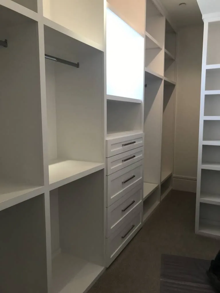 RM walk-in closet with white drawers, open shelves and hanging rails.